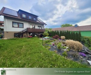 Einfamilienhaus Bitz zu verkaufen sofort einzugsbereit, Ansicht auf das Haus mit Teich und PV Anlage